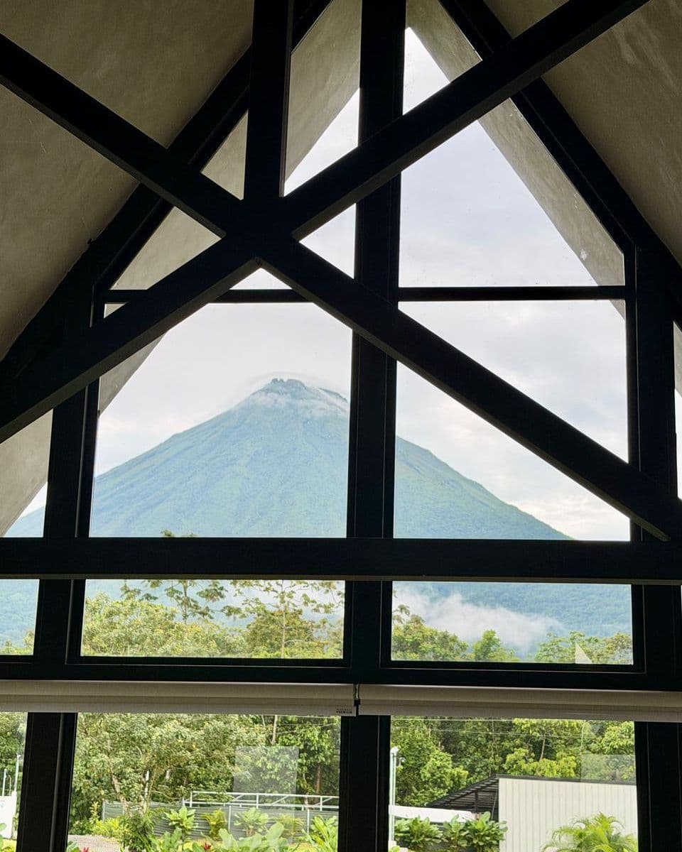 El ventanal triangular de la cabaña enmarcando el Volcán Arenal completo
