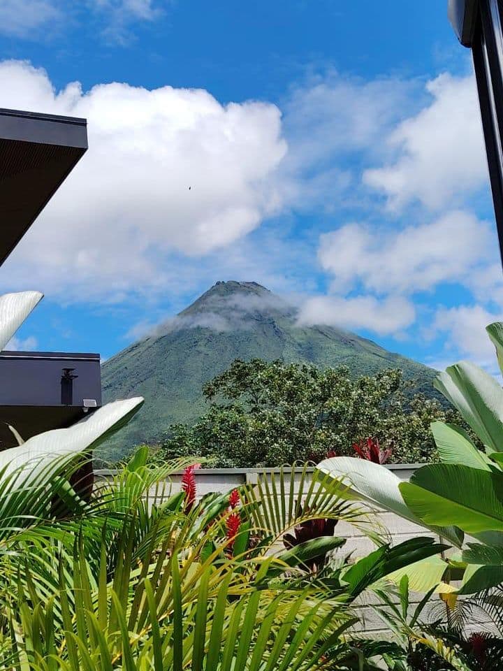 El Volcán Arenal visto desde una de las villas de Bike & Bed, enmarcado por el techo y la vegetación